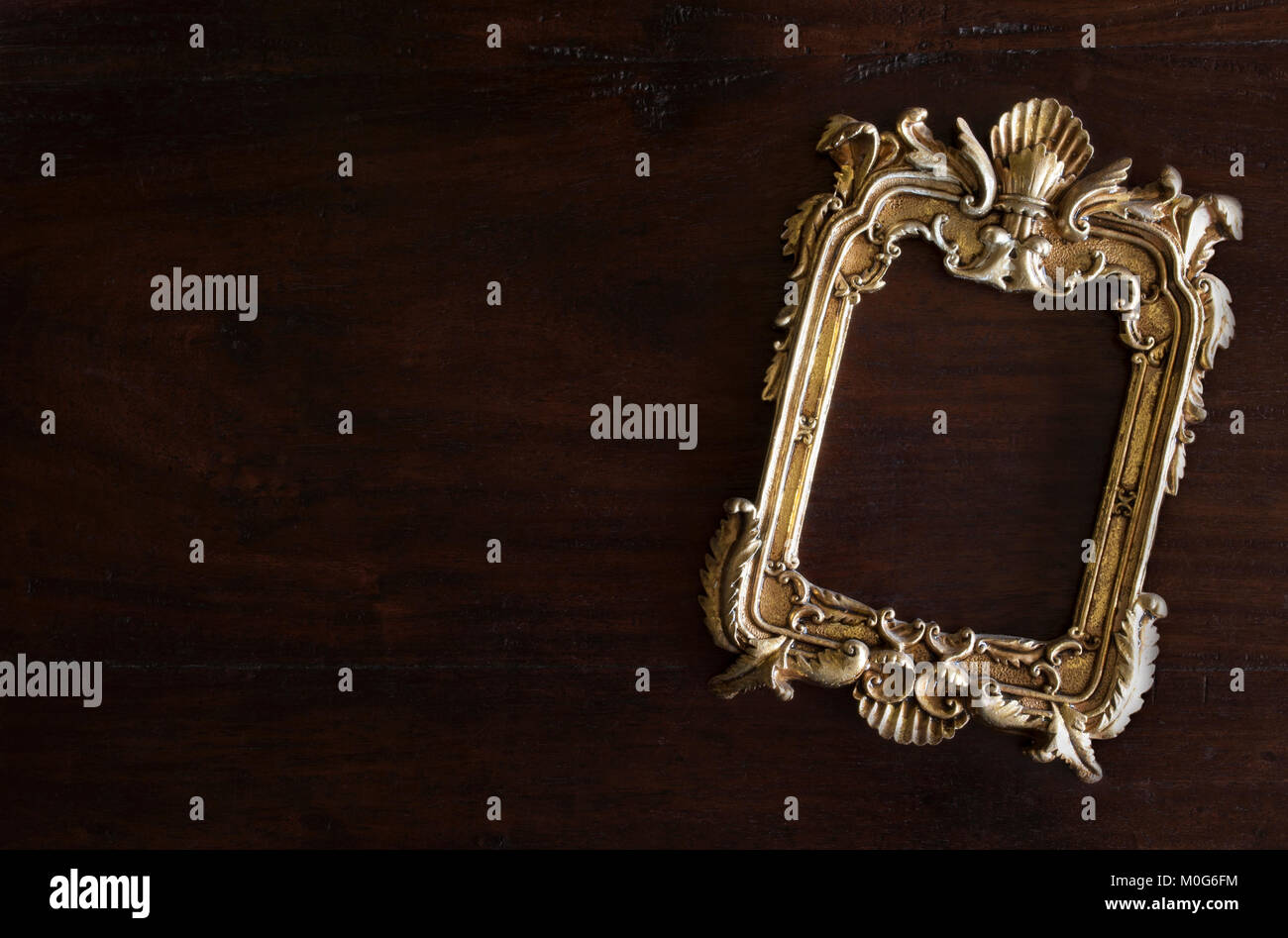 Antiq golden photo frame en estilo rococó, sobre fondo rústico de madera oscura Foto de stock