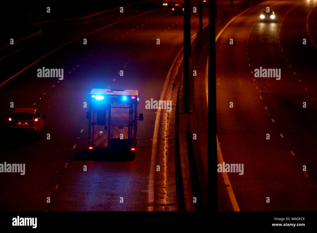 Ambulancia acelerando a lo largo de la autopista con las luces azules destellando en Irlanda del Norte, reino unido Foto de stock