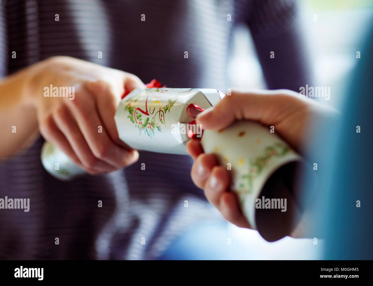 Dos personas tirando de un cracker de Navidad Foto de stock