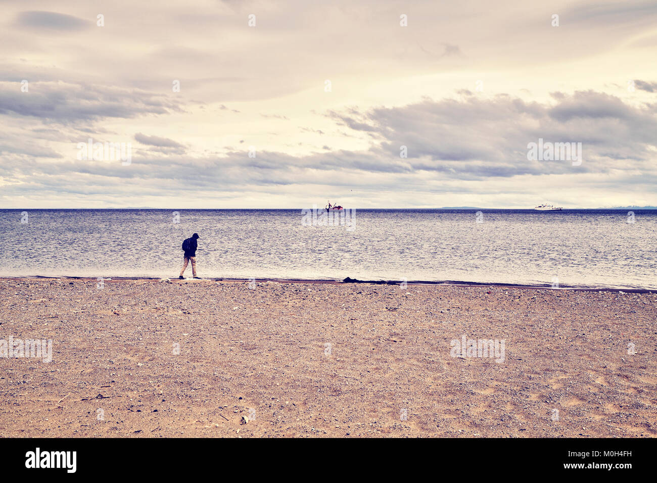 Persona solitaria camina por la playa, tonos de color imagen conceptual. Foto de stock