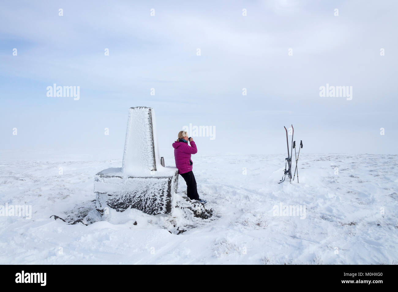Ski Tourer tomando un descanso en la Cumbre de Trig Burnhope Asiento en invierno, Cumbria/Condado de Durham frontera UK Foto de stock
