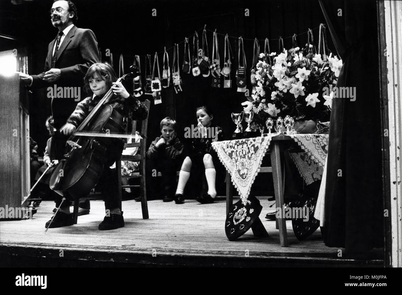 Joven tocando el violonchelo en el escenario de pueblo pequeño hall eisteddfod Llangynidr Gales Powys UK Foto de stock