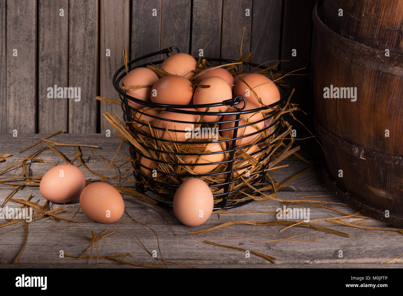 Brown pollo huevos en una canasta y sobre una superficie de madera rústica Foto de stock