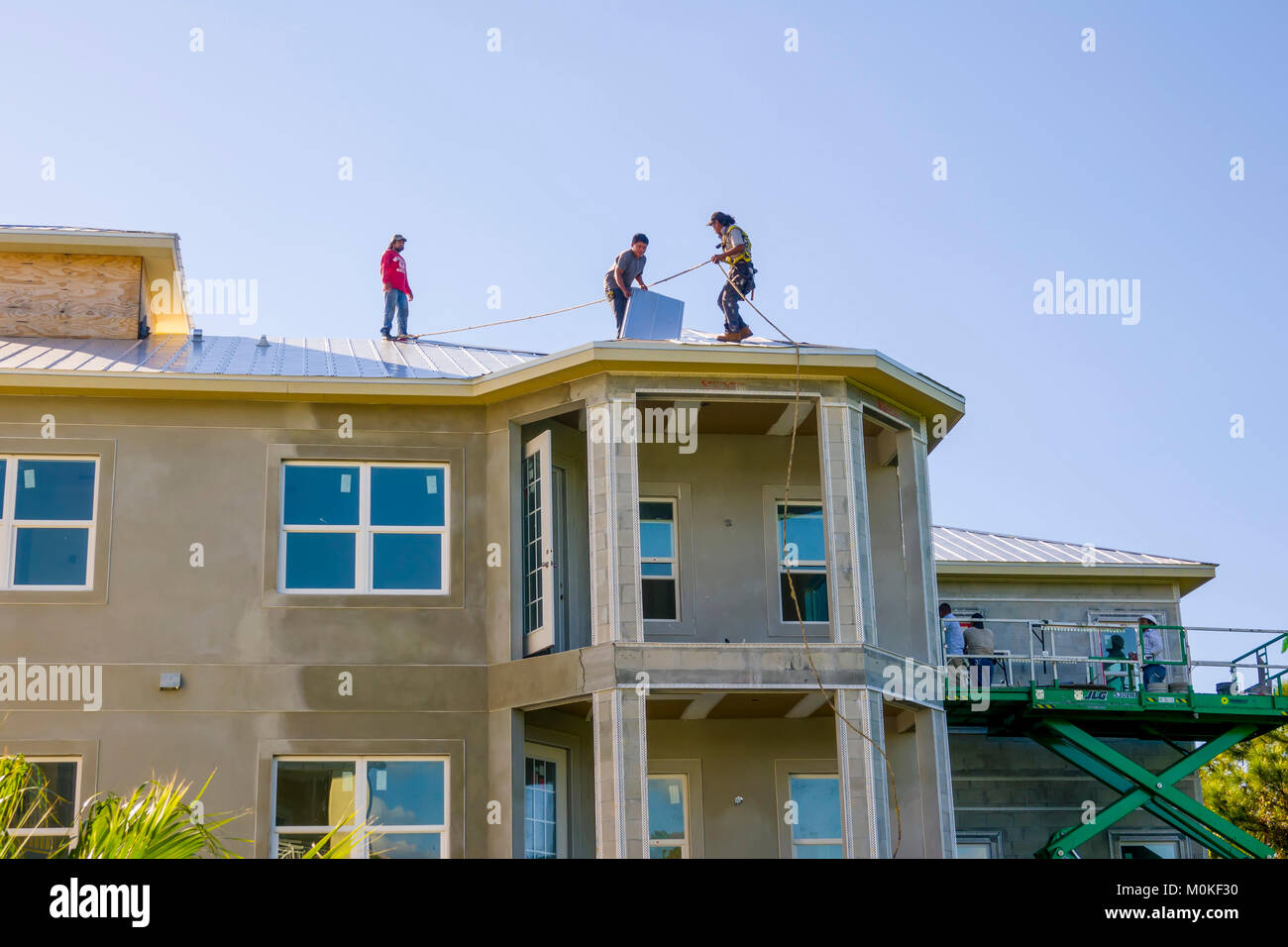 Los trabajadores de instalar un techo metálico encima de un condominio de nueva construcción Foto de stock