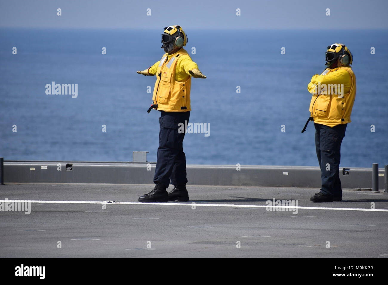 5ª Flota de EE.UU. ZONA DE OPERACIONES (Ene. 17, 2018) la aviación Boatswain's Mate de 2ª clase Handler Juan Troncoso (izquierda) lleva un helicóptero MH-60 como Aerotécnico Evelyn Valiente observa mientras está asignado al USS Lewis B. Extractor. El expedicionario plataforma base móvil admite la Fuerza Naval Anfibia, Task Force 51, 5ª Brigada Expedicionaria de la Marina las diversas misiones que incluyan la respuesta a las crisis, airborne remoción de contramedidas, contra-piratería operaciones, operaciones de seguridad marítima y de la ayuda humanitaria y de socorro en casos de desastre permitiendo misiones aunque TF 51/5 para ampliar su presencia en el mundo expedicionario más vo Foto de stock