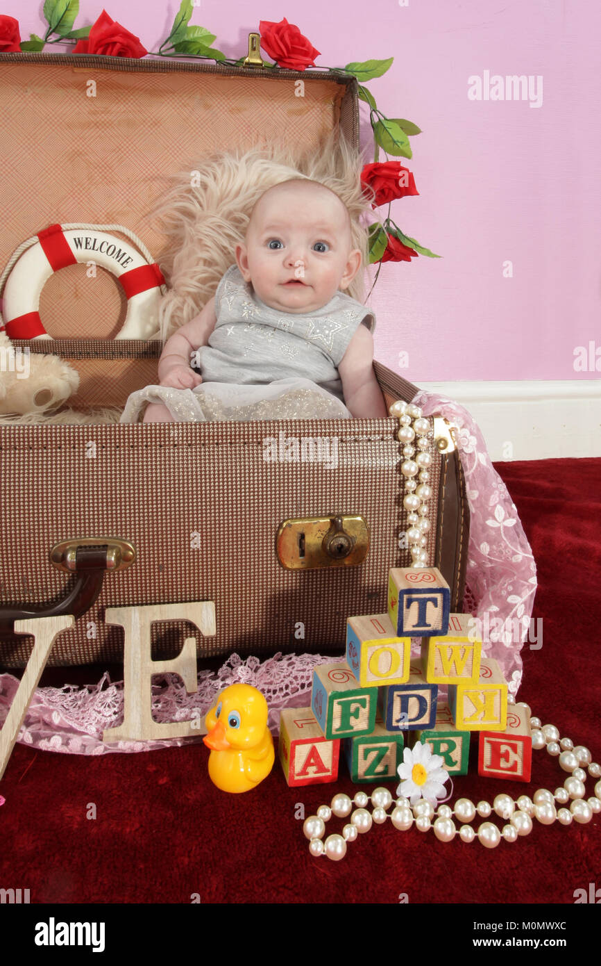 Pretty Little Girl, 4 mes de edad bebé niña jugando en la maleta llena de  juguetes Fotografía de stock - Alamy