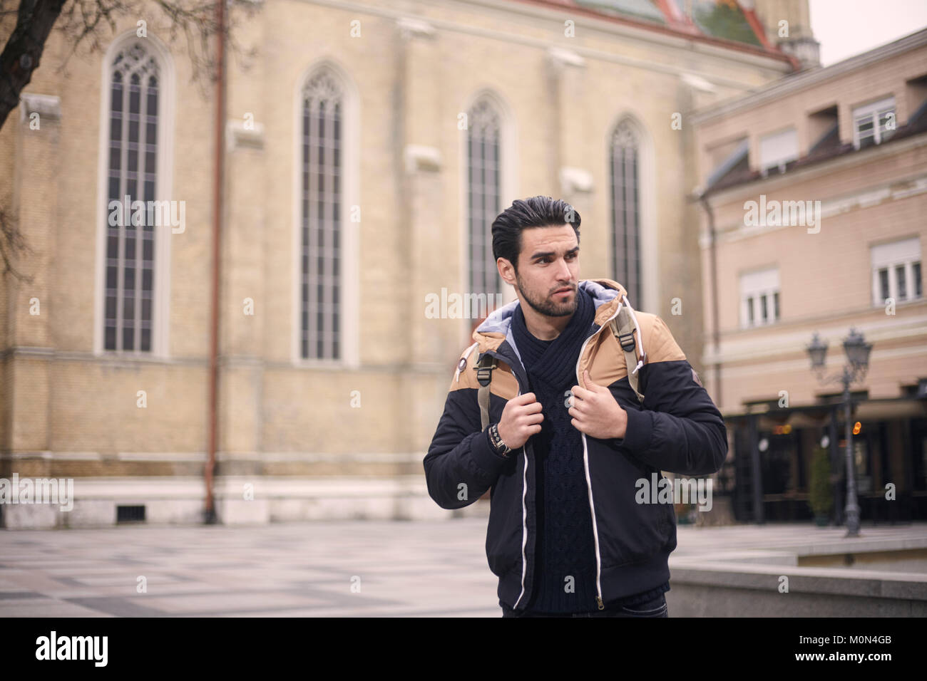 Un hombre joven, posando, vistiendo chaqueta, otoño/invierno de ropa. Ubicación urbana, vintage la arquitectura antigua. Ubicación: 'Novi Sad, Serbia'. Foto de stock