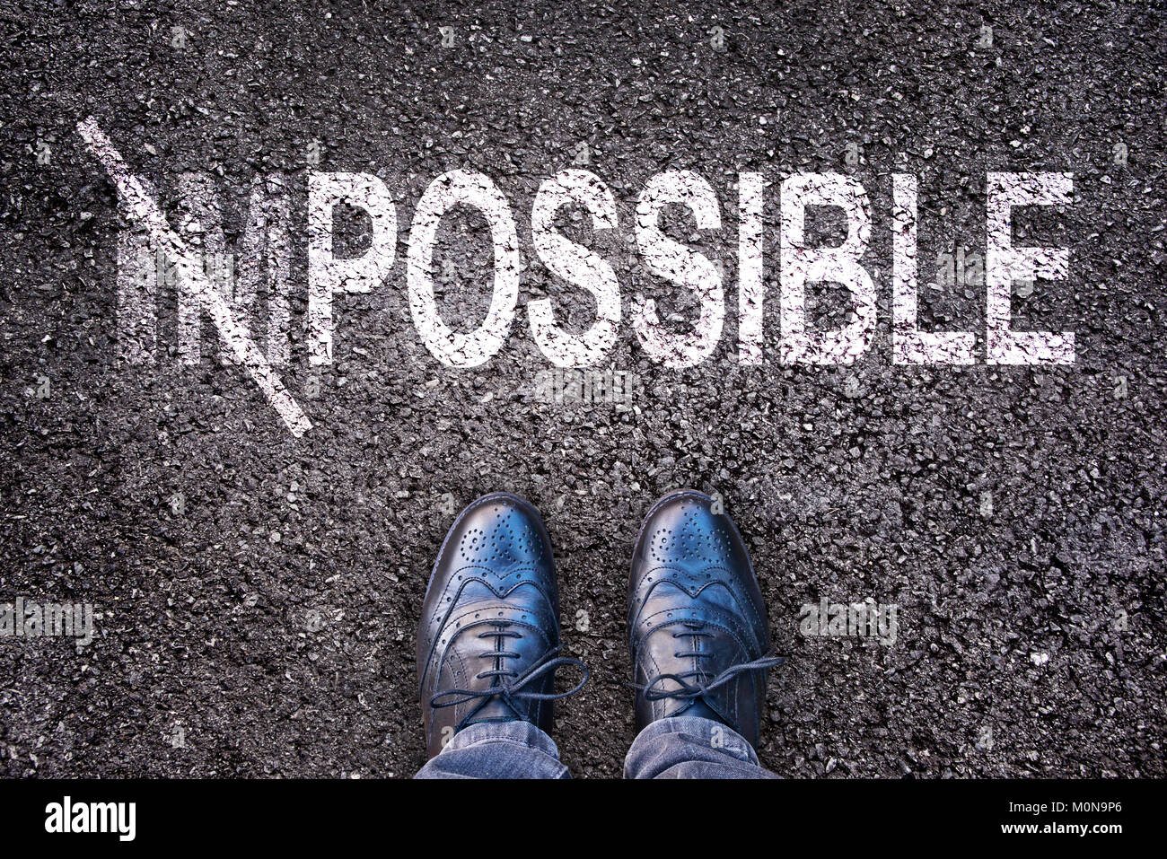 Cambiando la palabra imposible en posible en una carretera de asfalto con pies Foto de stock