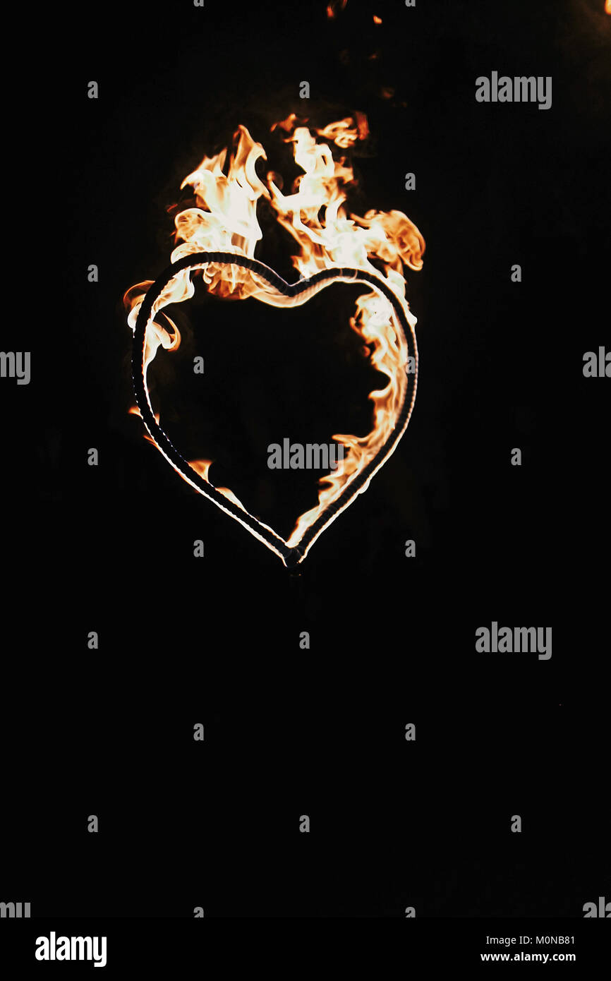 Fuegos artificiales en forma de corazón sobre fondo negro, espectáculo de fuego en la noche. Feliz Día de San Valentín tarjeta corazón ardiente fuego de Bengala. Espacio para el texto. Boda o valen Foto de stock
