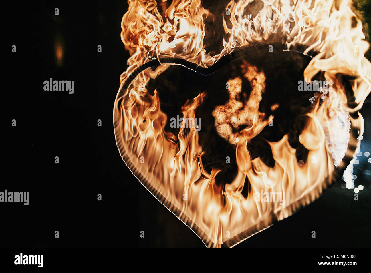 Fuegos artificiales en forma de corazón sobre fondo negro, espectáculo de fuego en la noche. Feliz Día de San Valentín tarjeta corazón ardiente fuego de Bengala. Espacio para el texto. Boda o valen Foto de stock
