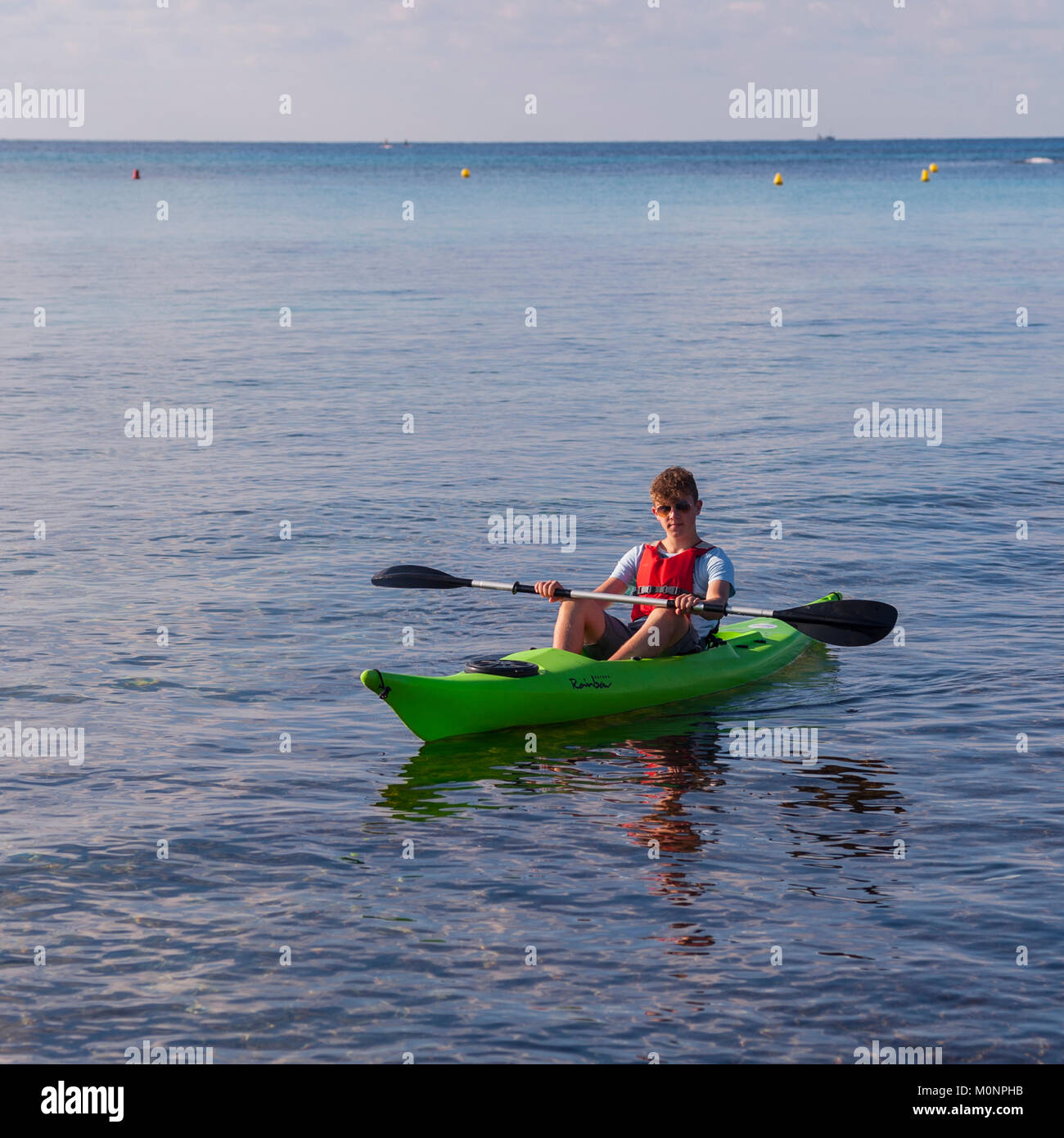 Un adolescente en un Kayak en Punta Prima, Menorca, Islas Baleares, España Foto de stock