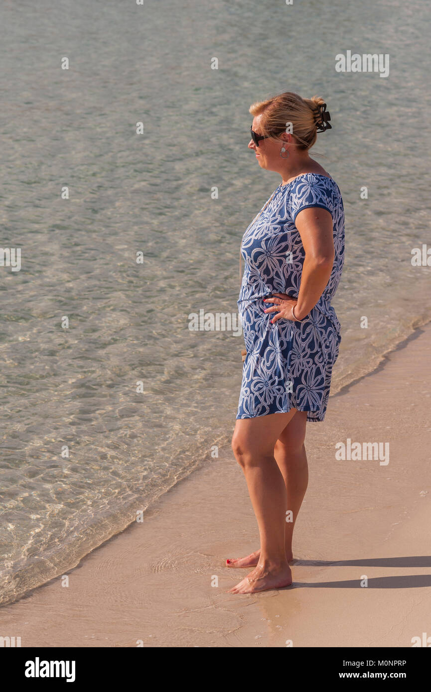 Una mujer de pie en la playa de Punta Prima, Menorca, Islas Baleares, España Foto de stock