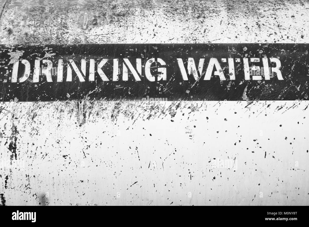 Una fotografía en blanco y negro de un cartel que decía la etiqueta 'Drinking Agua' en el lateral de un camión cisterna de agua. Foto de stock