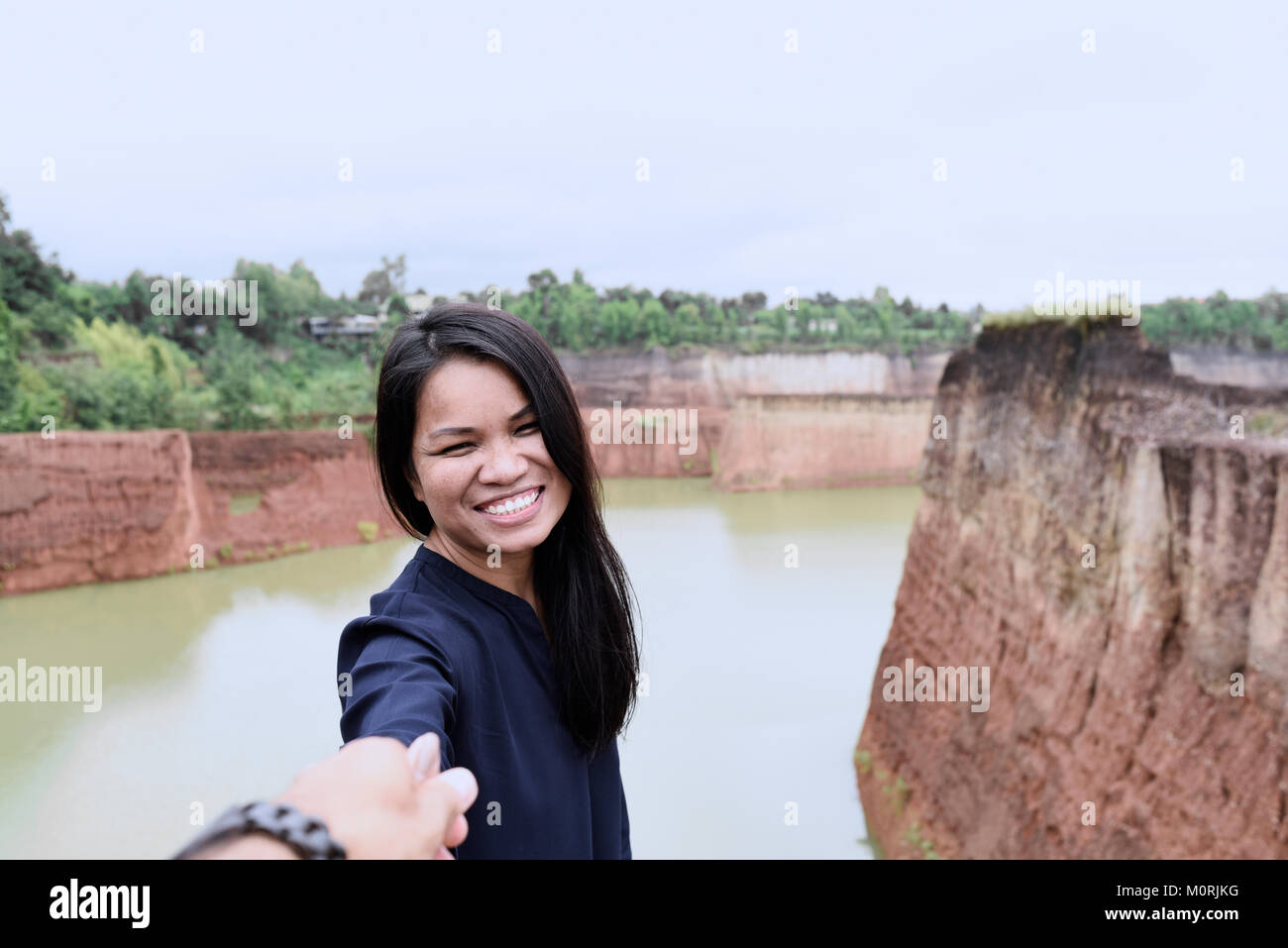 Bonita mujer asiática sosteniendo la mano de su compañero invitando a ir y explorar juntos. Foto de stock