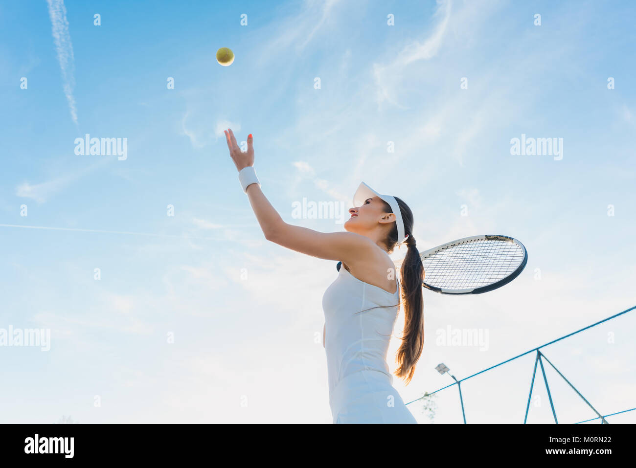 Mujer jugando al tenis dando servicio Foto de stock