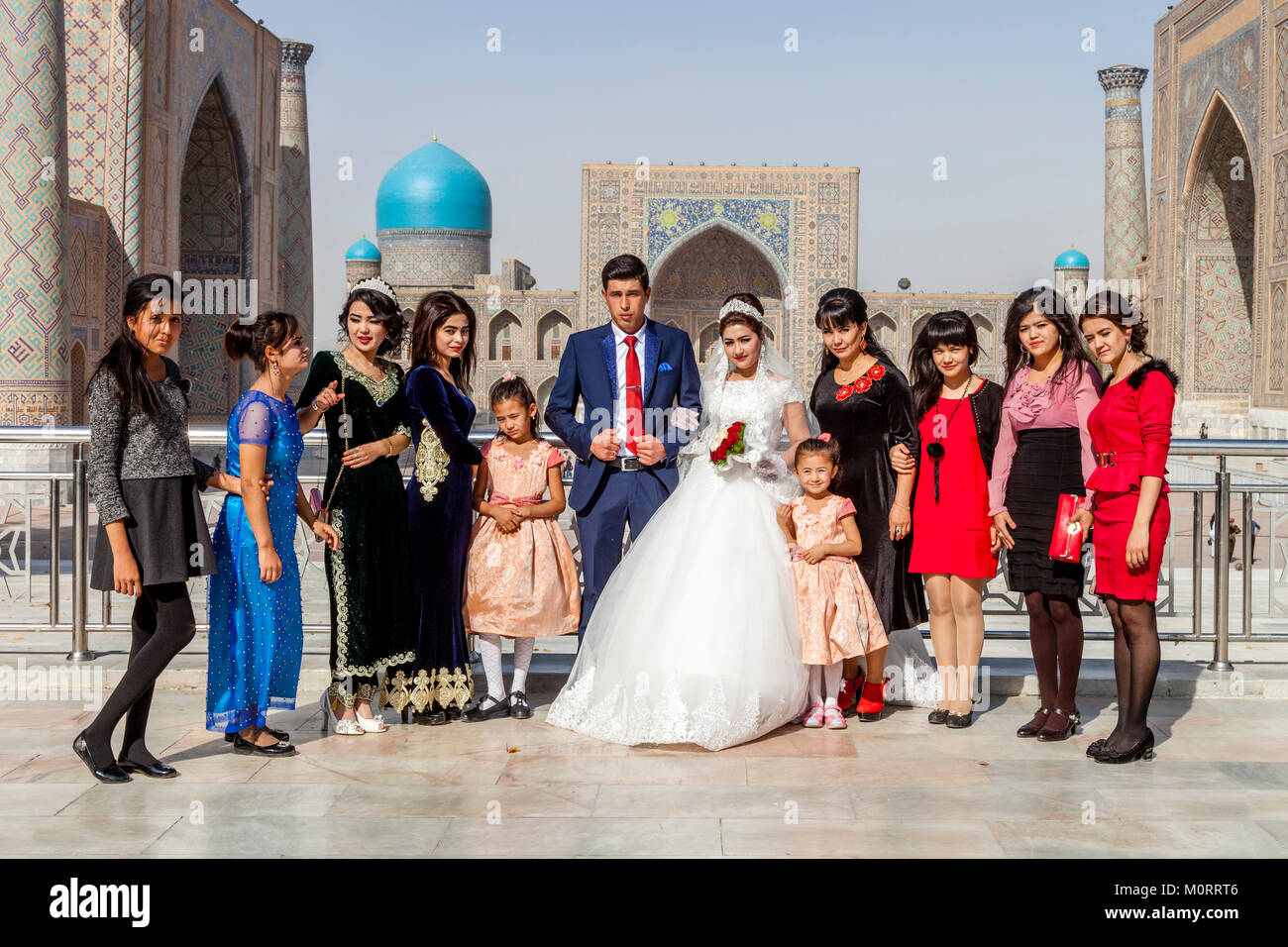 Una fiesta de boda posa para las fotos en el Registán compleja, Samarcanda, Uzbekistán Foto de stock