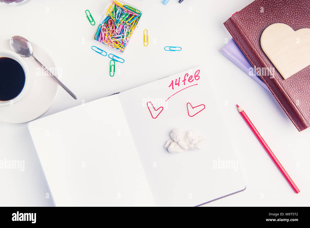 Escritura roja número catorce de febrero, Día de San Valentín texto y ángeles stauette el organizador personal en el lugar de trabajo. Concepto de planificación del día de San Valentín. El enfoque selectivo. Foto de stock
