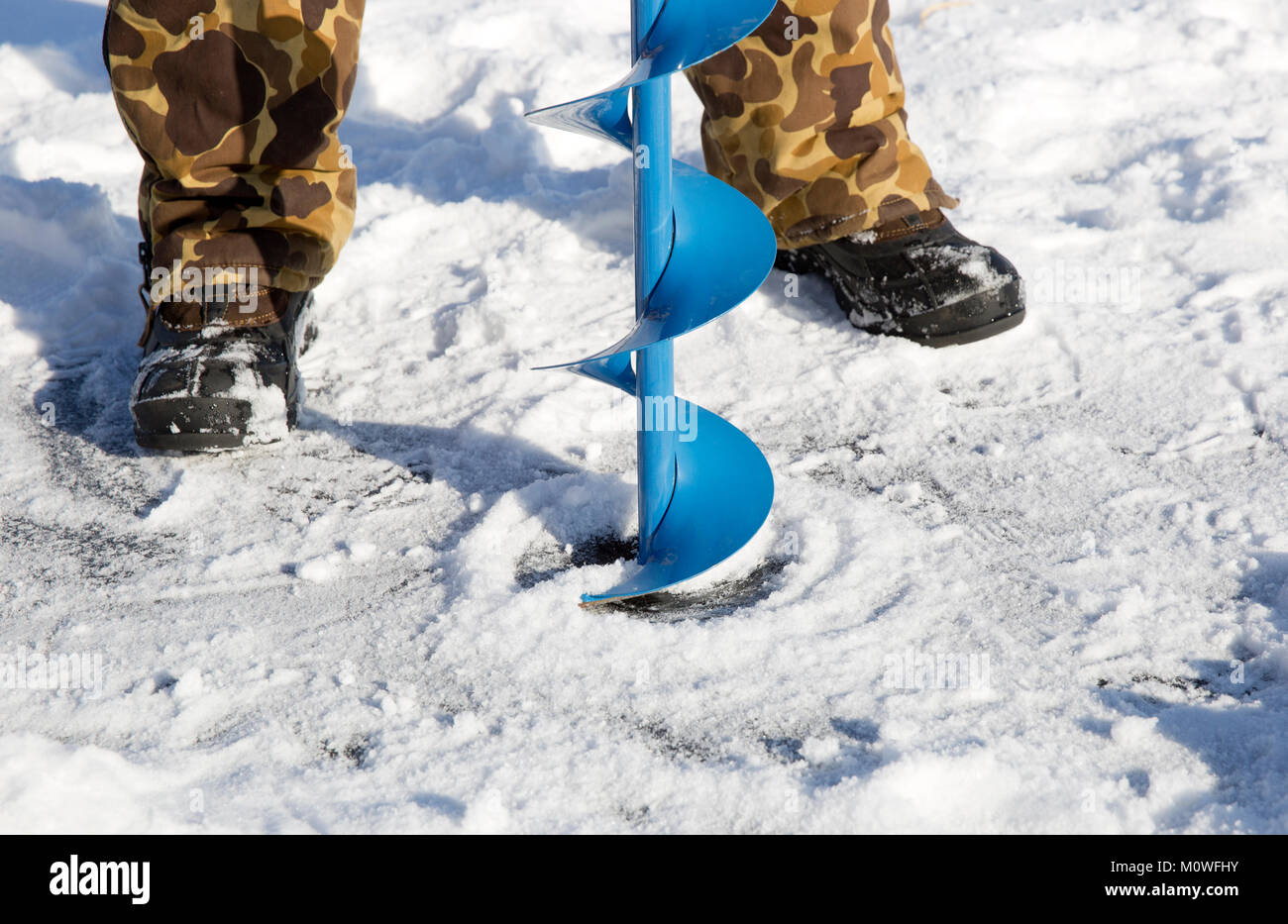 Una persona la perforación de un agujero en el hielo de un lago congelado utilizando un hielo auguer (un tornillo helicoidal blade). Foto de stock