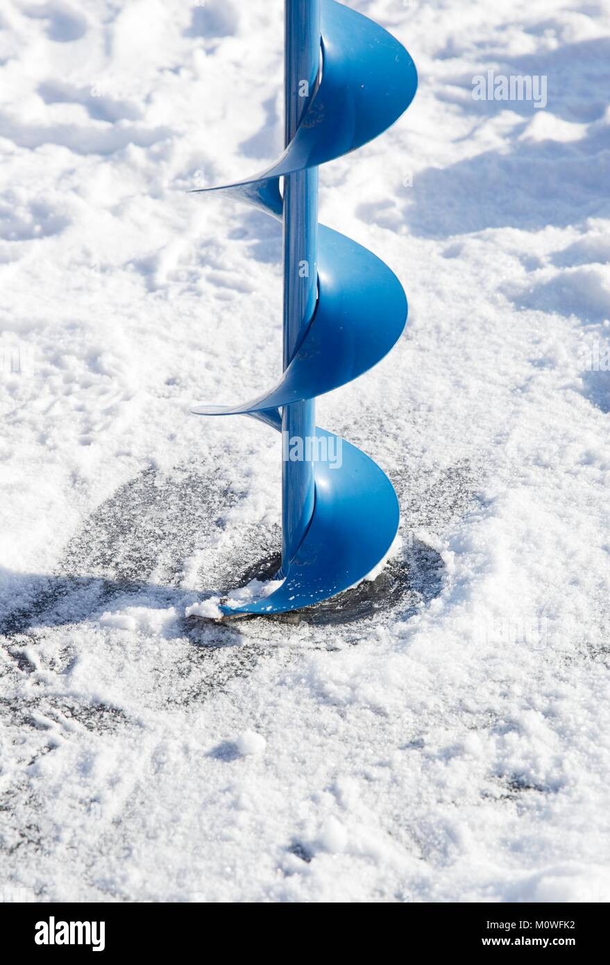 Un sinfín de hielo (un tornillo helicoidal blade) comenzando a taladrar un agujero en el hielo de un lago congelado para pescar en el hielo. Foto de stock