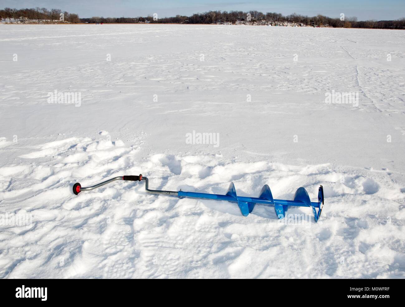 Un sinfín de hielo azul (un tornillo helicoidal blade) tendido en la nieve sobre un lago congelado en Minnesota, EE.UU. Foto de stock