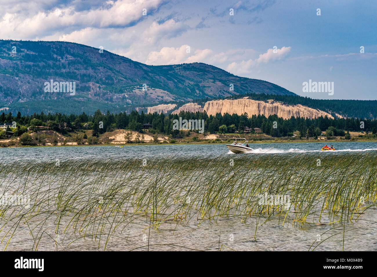Lancha tirando de la mujer y la niña en el bote de goma, el lago Windermere, Columbia Valley, Purcell Mountains, cerca de Invermere, British Columbia, Canadá Foto de stock
