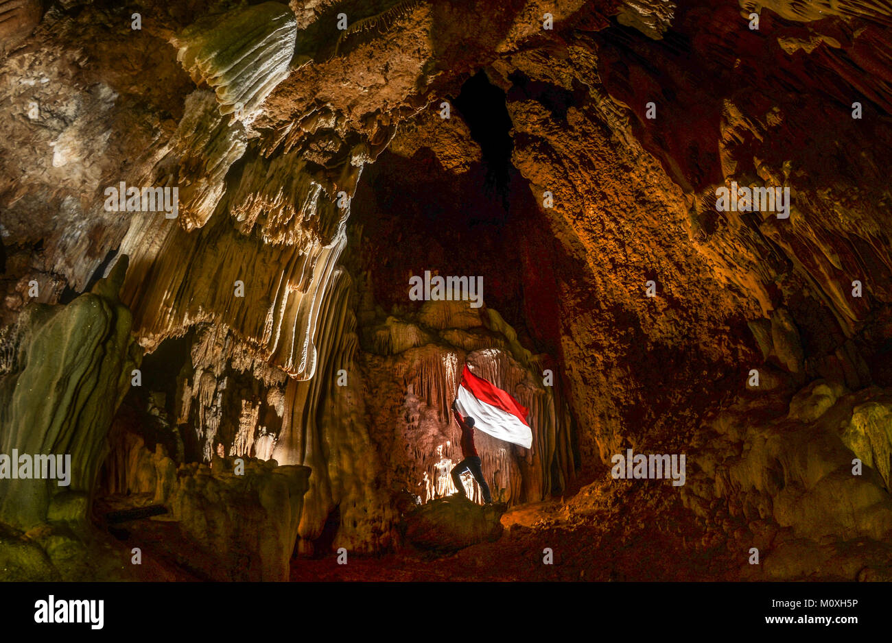 Elevar la bandera nacional de Indonesia en la antigua cueva de Rammang Rammang, al sur de Sulawesi, Indonesia. La cueva nombre es 'Gua Kunang-Kunang' Foto de stock