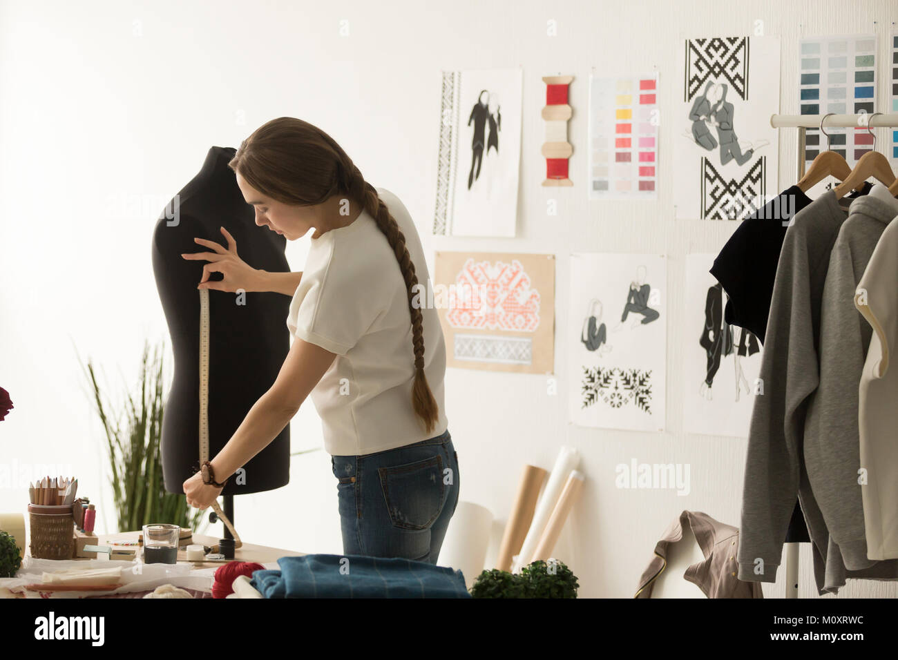 Adaptar, tomando mediciones con cinta métrica en diseño de moda Foto de stock