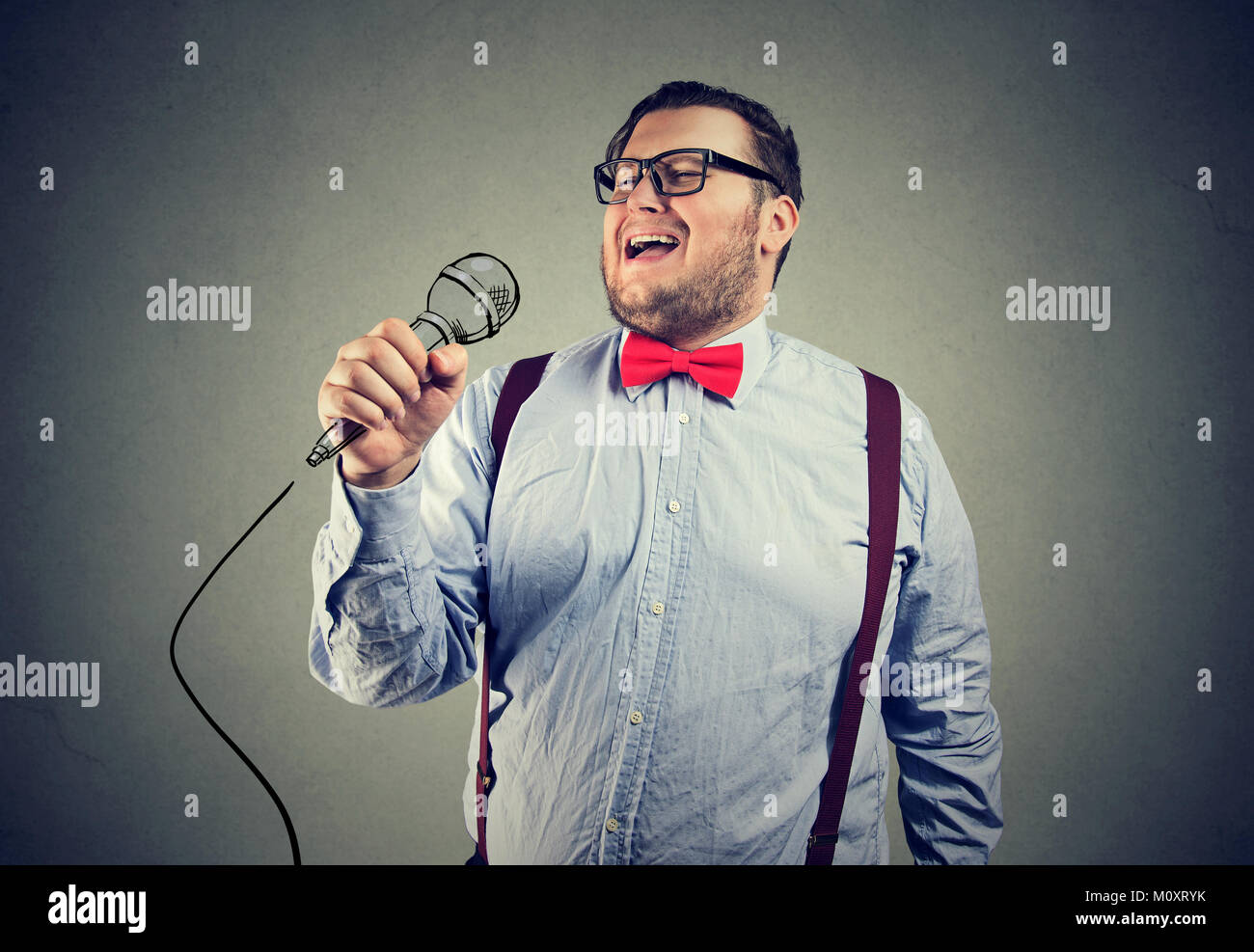 Joven hombre gordito en traje formal y gafas cantando con profunda