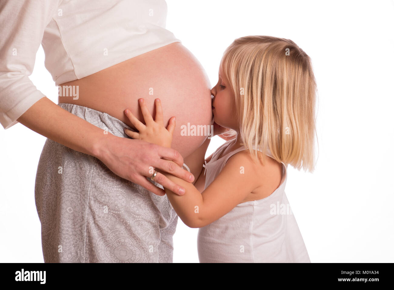 Niña abrazando a la madre embarazada y besar su vientre Foto de stock