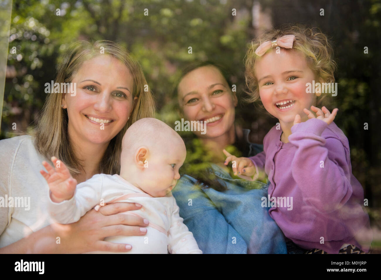 Madres e Hijas caucásica ondeando detrás de la ventana Foto de stock