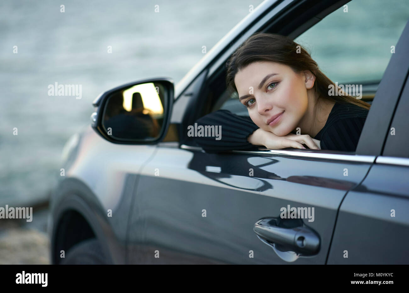 Sonriente mujer caucásica inclinándose en car window Foto de stock