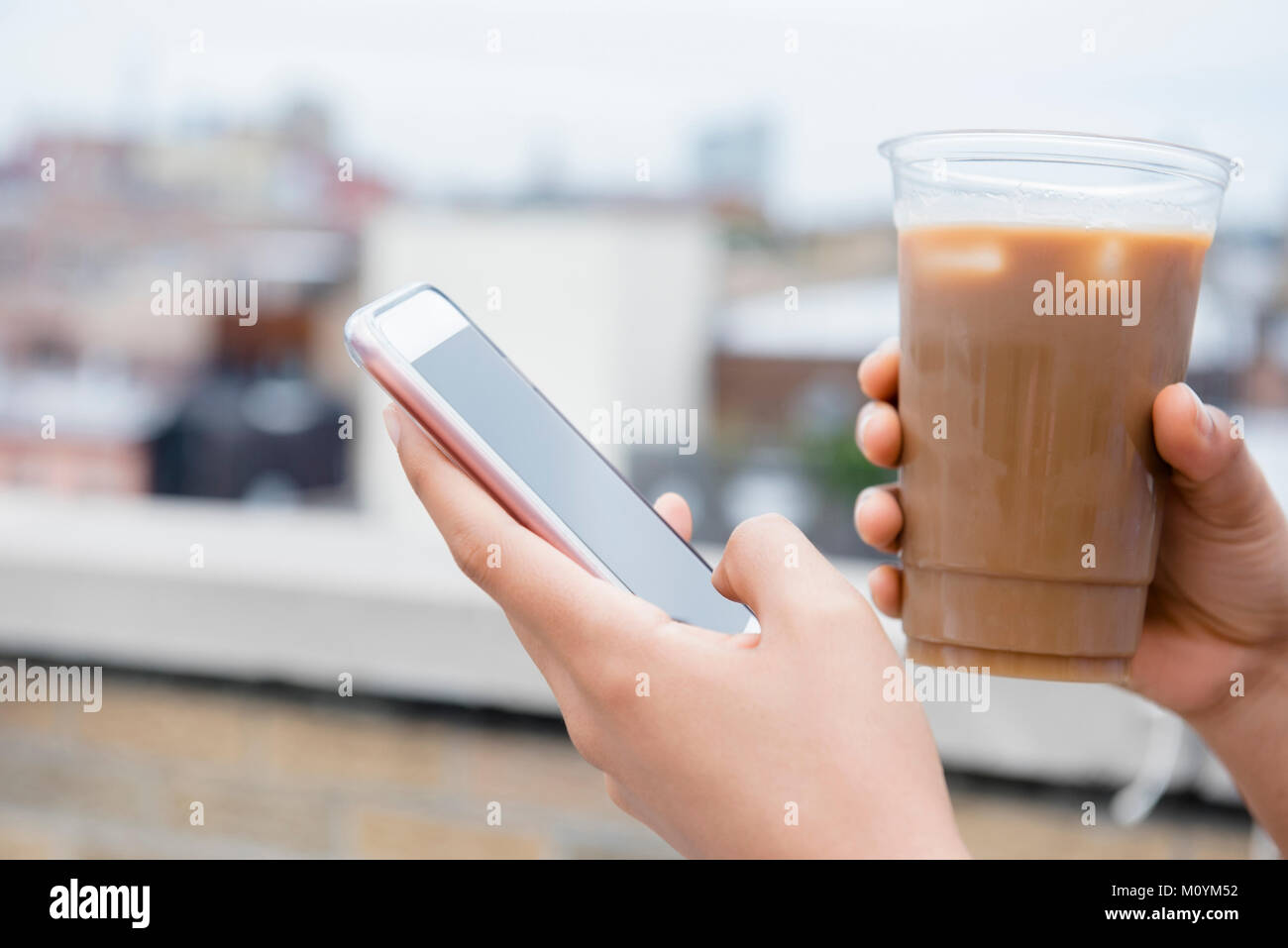 Manos de Afroamericana bebiendo café y los mensajes de texto por teléfono celular Foto de stock