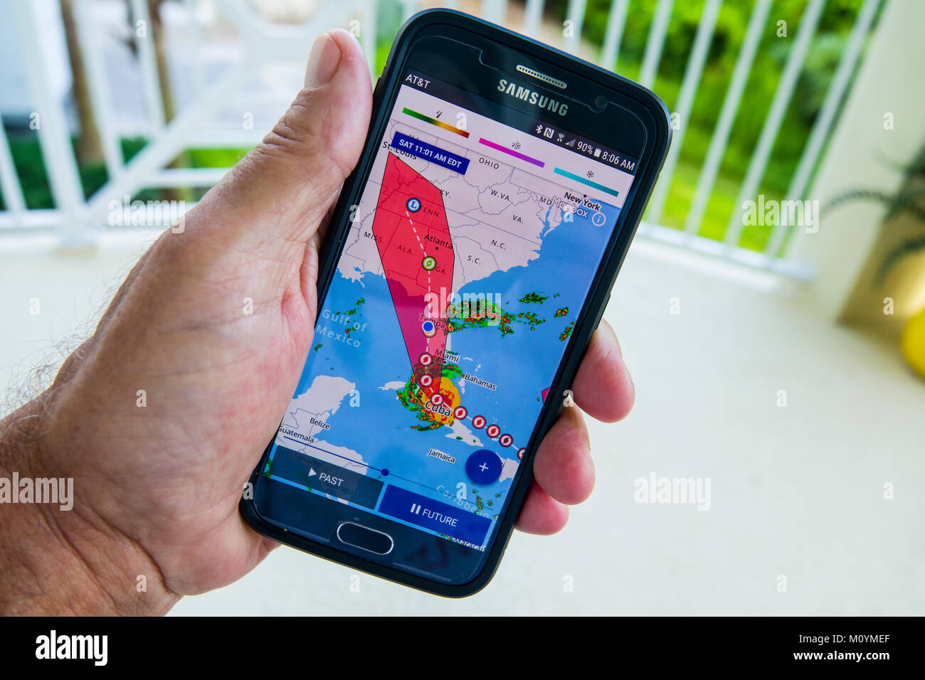 Siguiente y seguimiento de una advertencia de huracán Irma en la televisión la televisión y un teléfono móvil smartphone dispositivo de mano Foto de stock