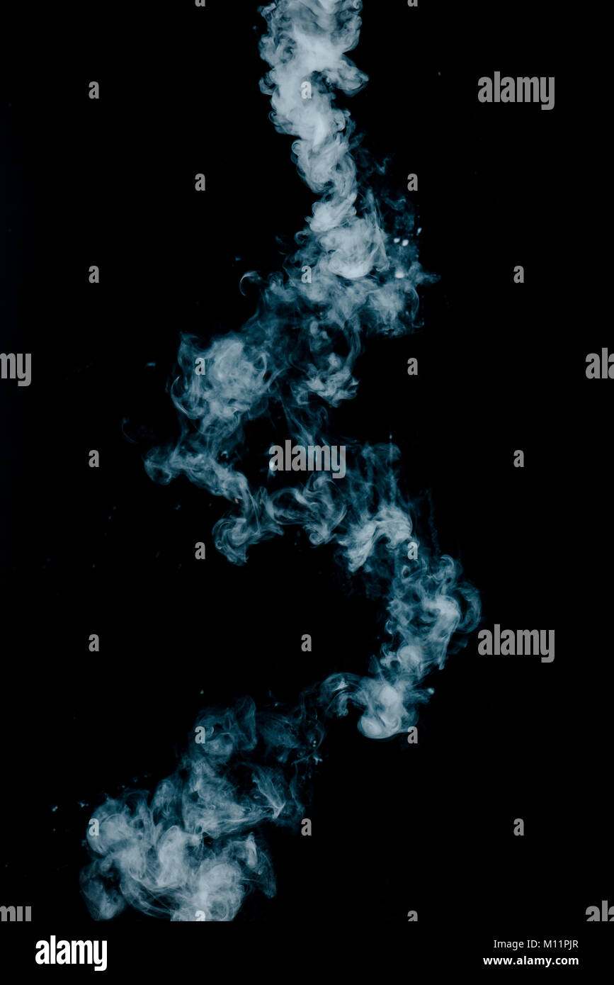 Textura de vapor desde una bebida caliente sobre un fondo negro. Humo azul con espacio de copia. Foto de stock