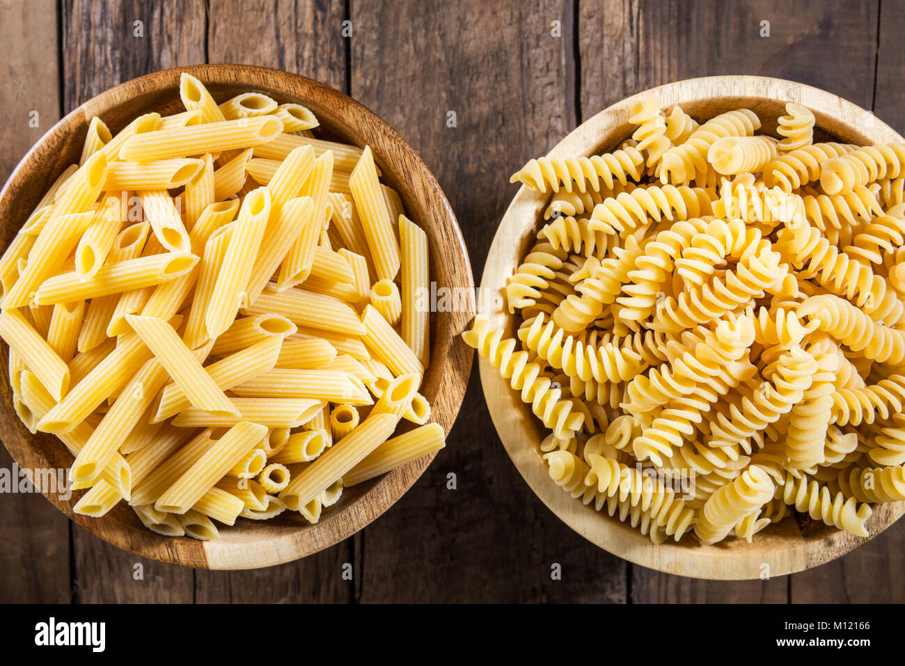 Diferentes tipos de pasta cruda como Fusilli y Penne Rigate sobre fondo