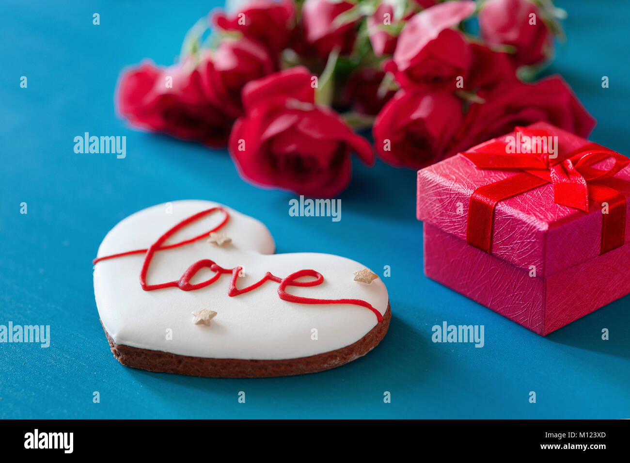 Caja de regalo y ramo de rosas y pan de jengibre en forma de corazón con la inscripción amor por vacaciones en el fondo de madera. Día de la madre, feliz cumpleaños , el día de la mujer. Día de San Valentín Foto de stock