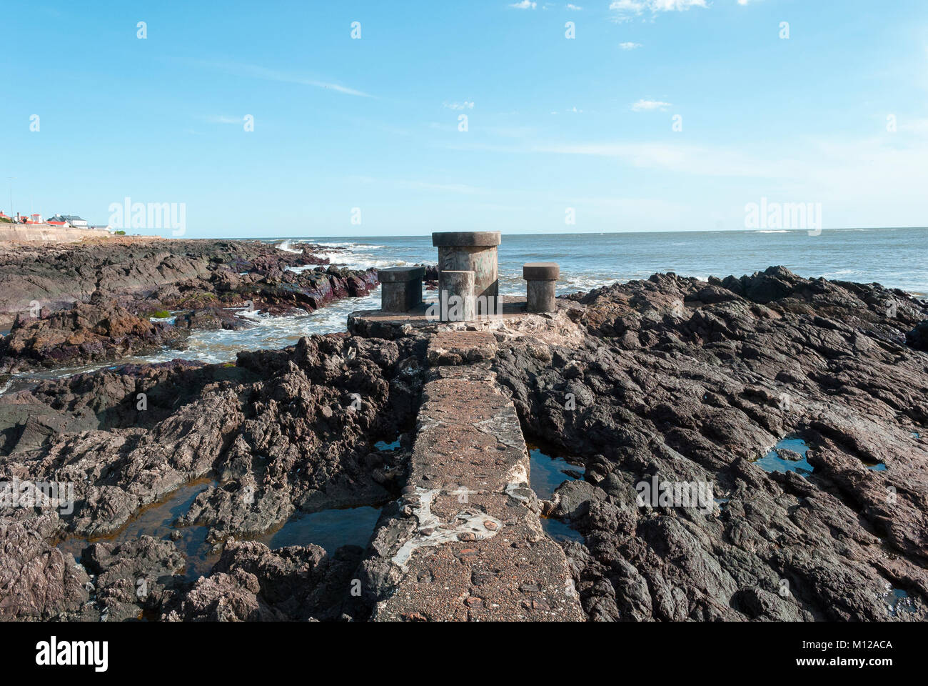 Camino que conduce a una mesa y sillas de hormigón en una playa aislada de rocas. Punta del Este, Uruguay Foto de stock