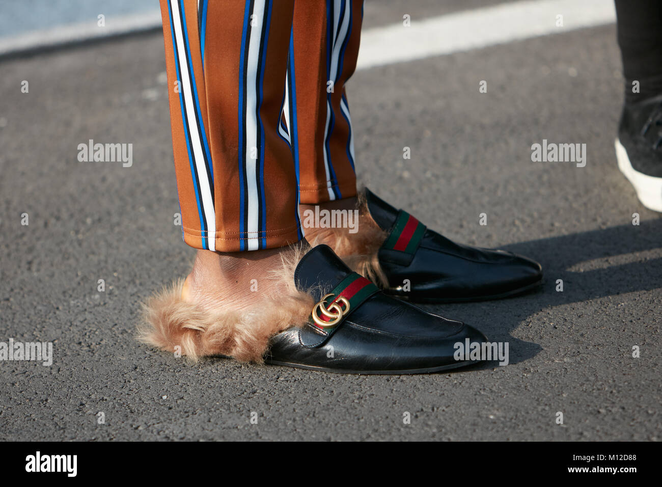 Milán - 14 de enero: el hombre con Gucci zapatillas con pieles y pantalón  rayado antes de