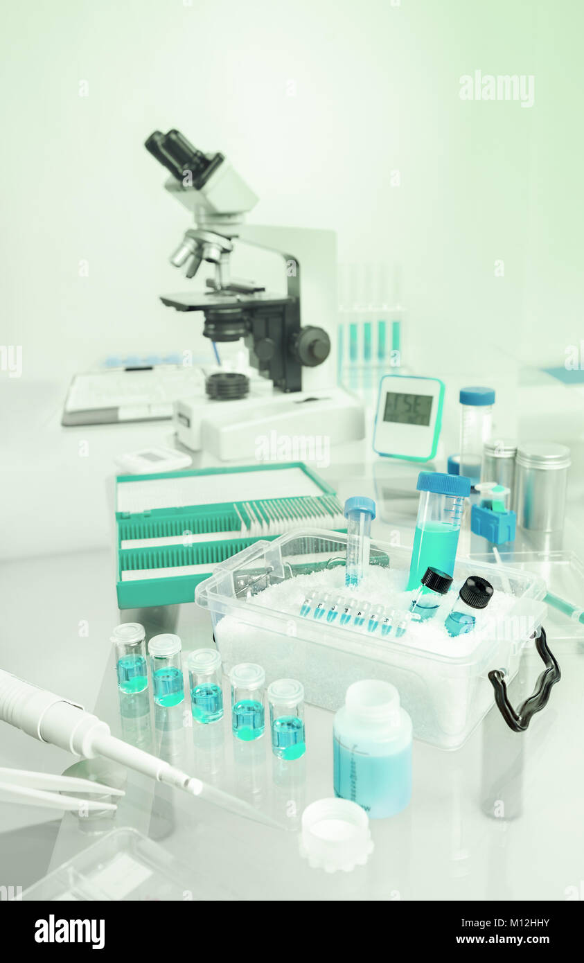 Antecedentes científicos con muestras, pipeta, cesta de hielo y microscopio en gris y azul, espacio para el texto en la parte superior Foto de stock