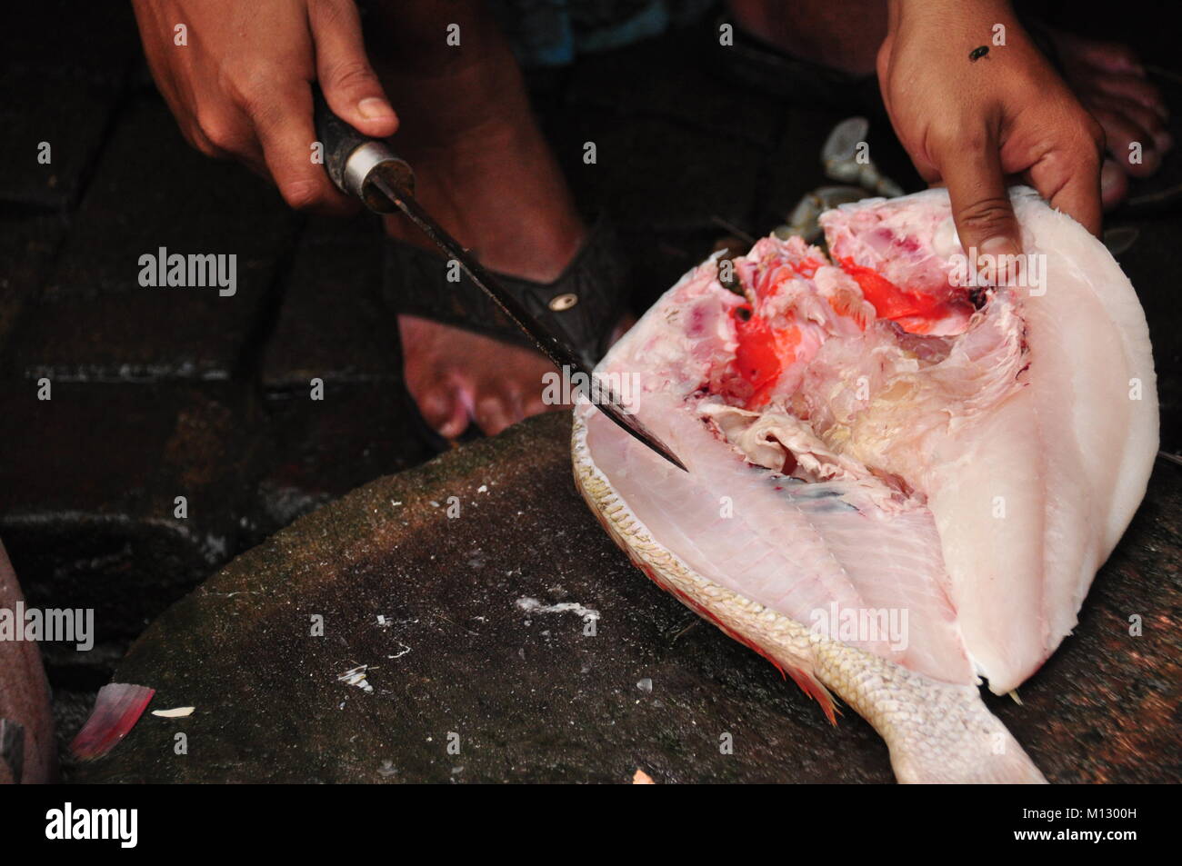 Destripar el pescado con un machete. Preparando una comida. Foto de stock