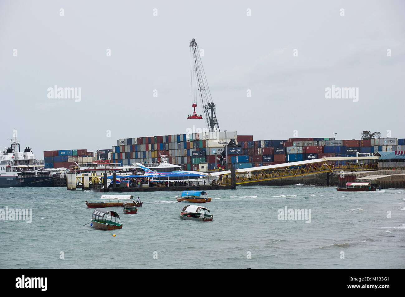 La carga de contenedores en un barco de contenedores en el puerto de  Zanzíbar, Tanzania, en un día soleado con los dhows en primer plano  Fotografía de stock - Alamy