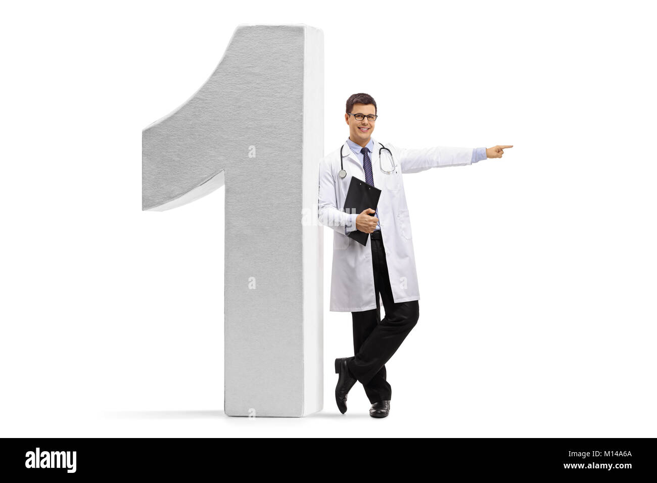Longitud total retrato de un médico apoyado contra una figura número uno y apuntando aislado sobre fondo blanco. Foto de stock