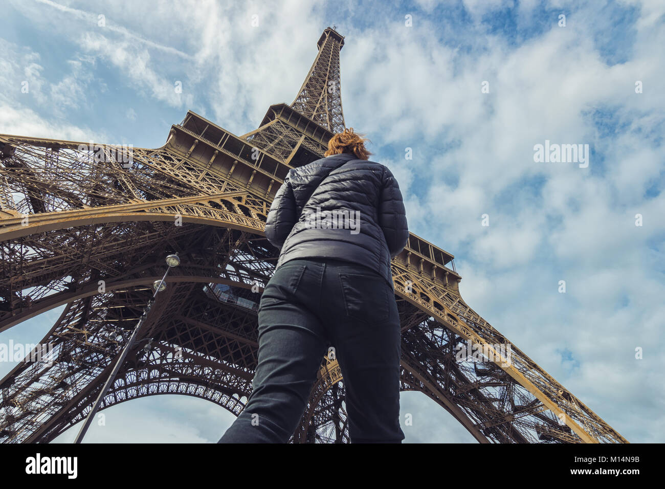 La mujer pasa por debajo de la torre Eiffel en París. Foto de stock
