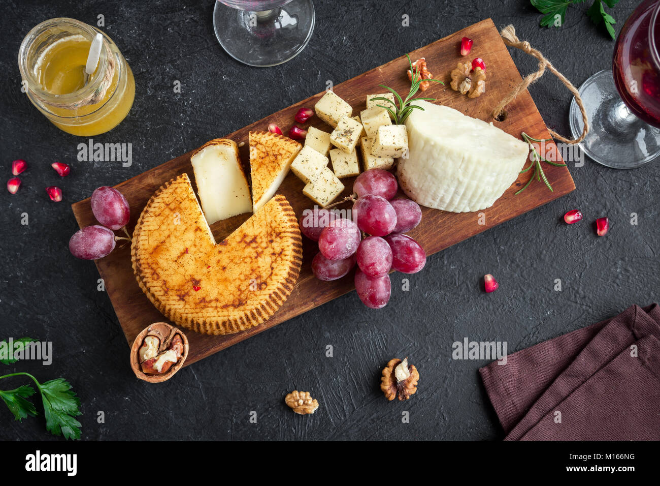 Tabla de quesos con un surtido de quesos, uvas, nueces, sobre fondo