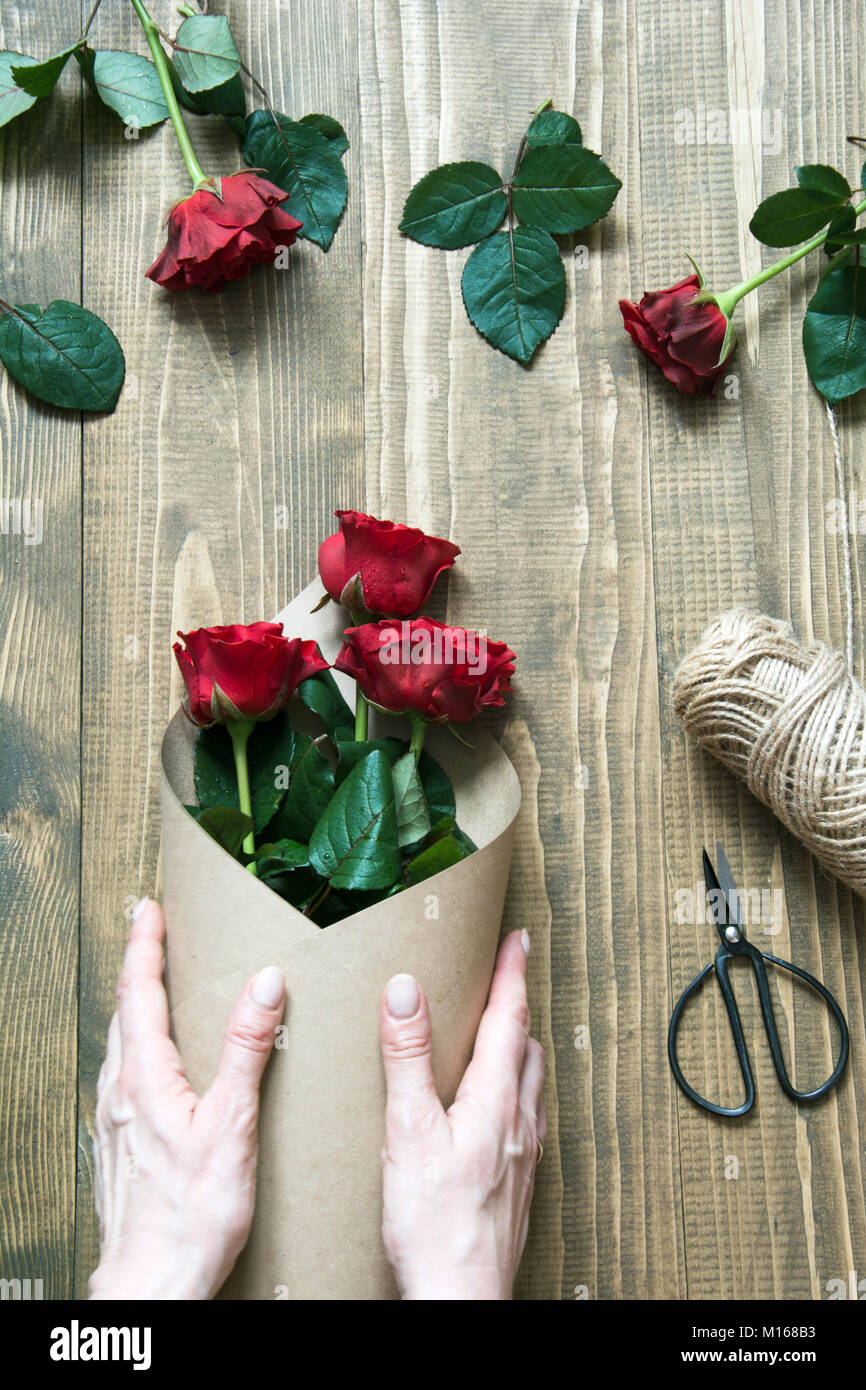 Floristería haciendo un ramo de rosas rojas, envolver en papel kraft en una  mesa de madera. Vista desde arriba. Estilo rústico Fotografía de stock -  Alamy