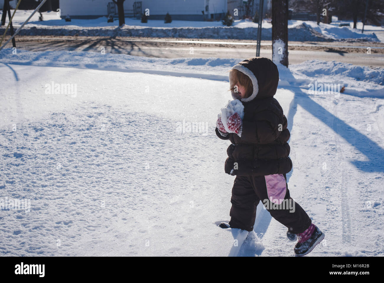 Un niño de 3 años vistiendo la ropa de invierno, guantes de invierno, juega la en un soleado día de invierno en los Estados Unidos Fotografía de stock - Alamy