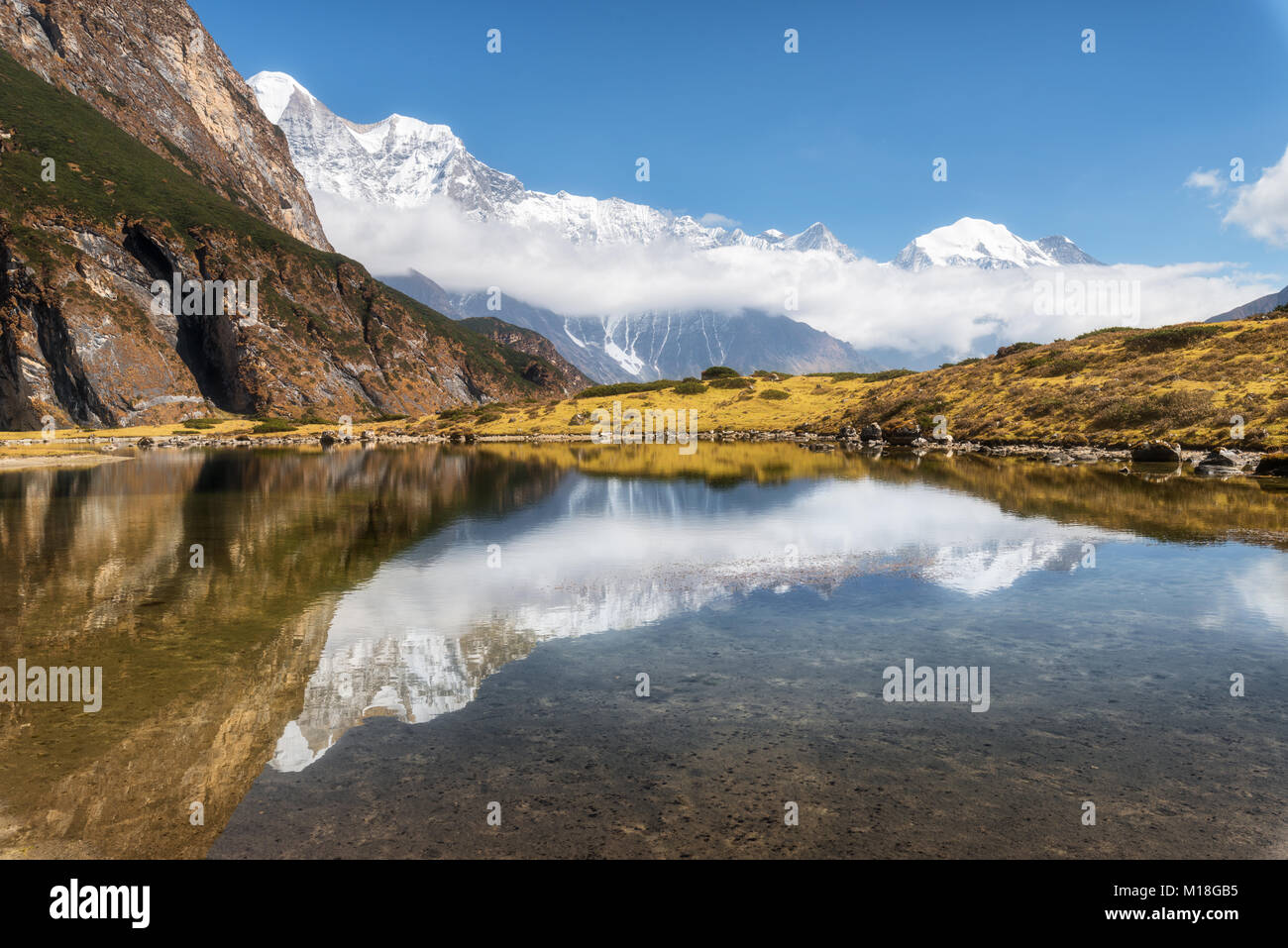Majestuosas montañas con altas rocas con picos nevados, lagos de montaña, hermoso reflejo en el agua, el cielo azul con nubes en el atardecer. Nepal. Amazi Foto de stock