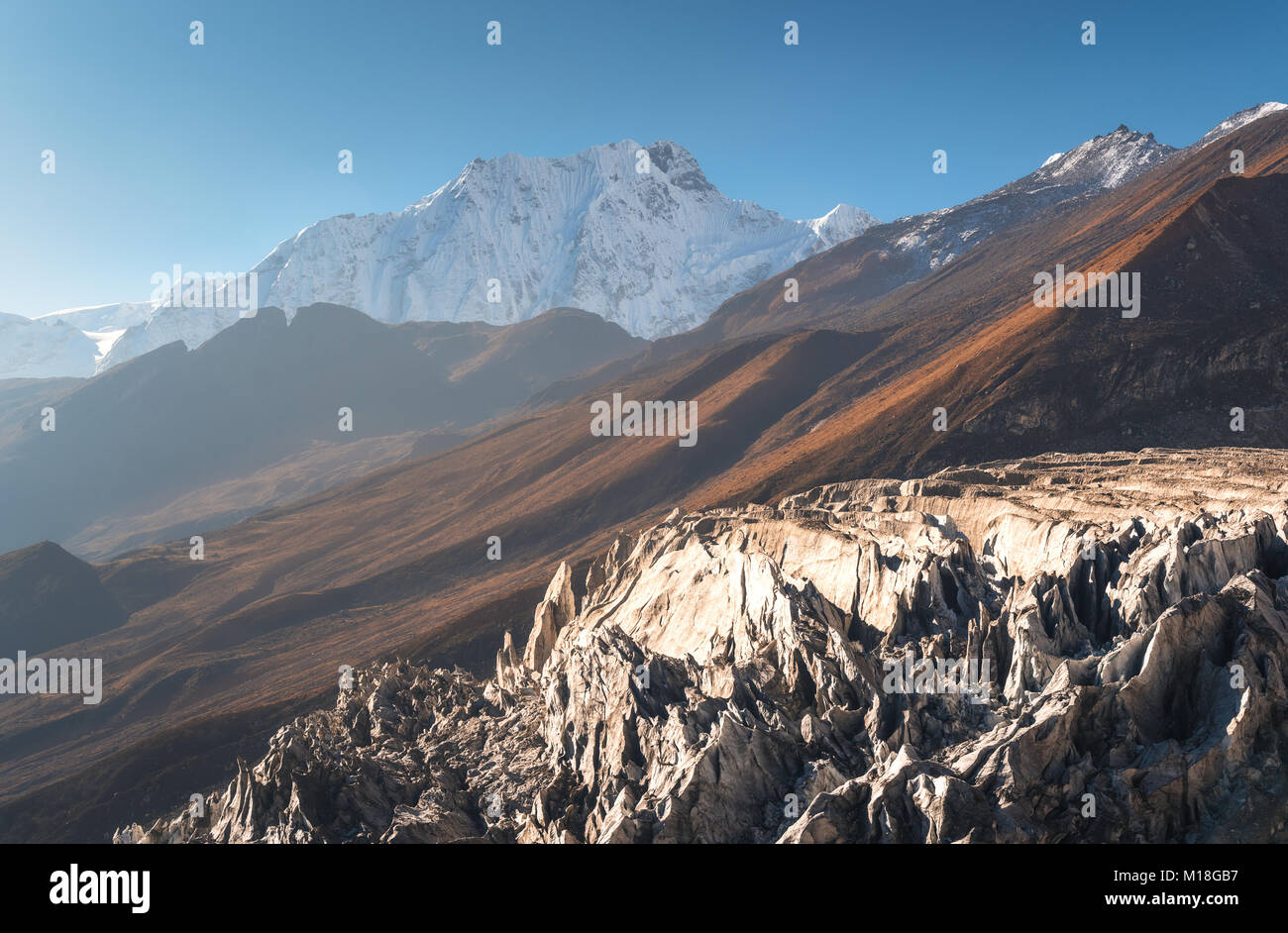 Hermosas vistas de montañas cubiertas de nieve contra el cielo azul al amanecer en Nepal. Paisaje con los picos nevados de las montañas del Himalaya, glaciar, rocas, colinas Foto de stock