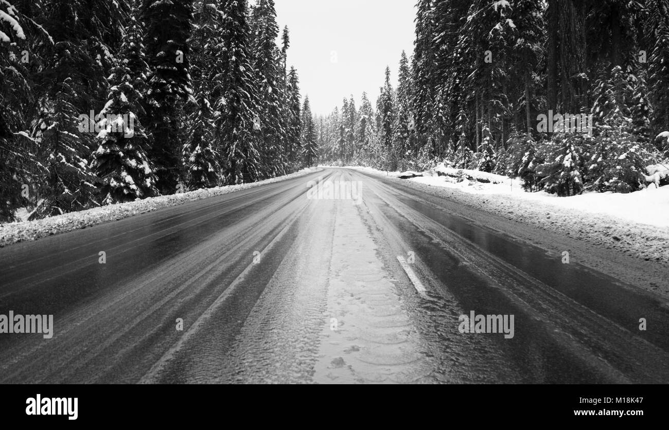 Una nueva capa de nieve ha aparecido en una carretera cortada por las montañas en el estado de Oregon Foto de stock