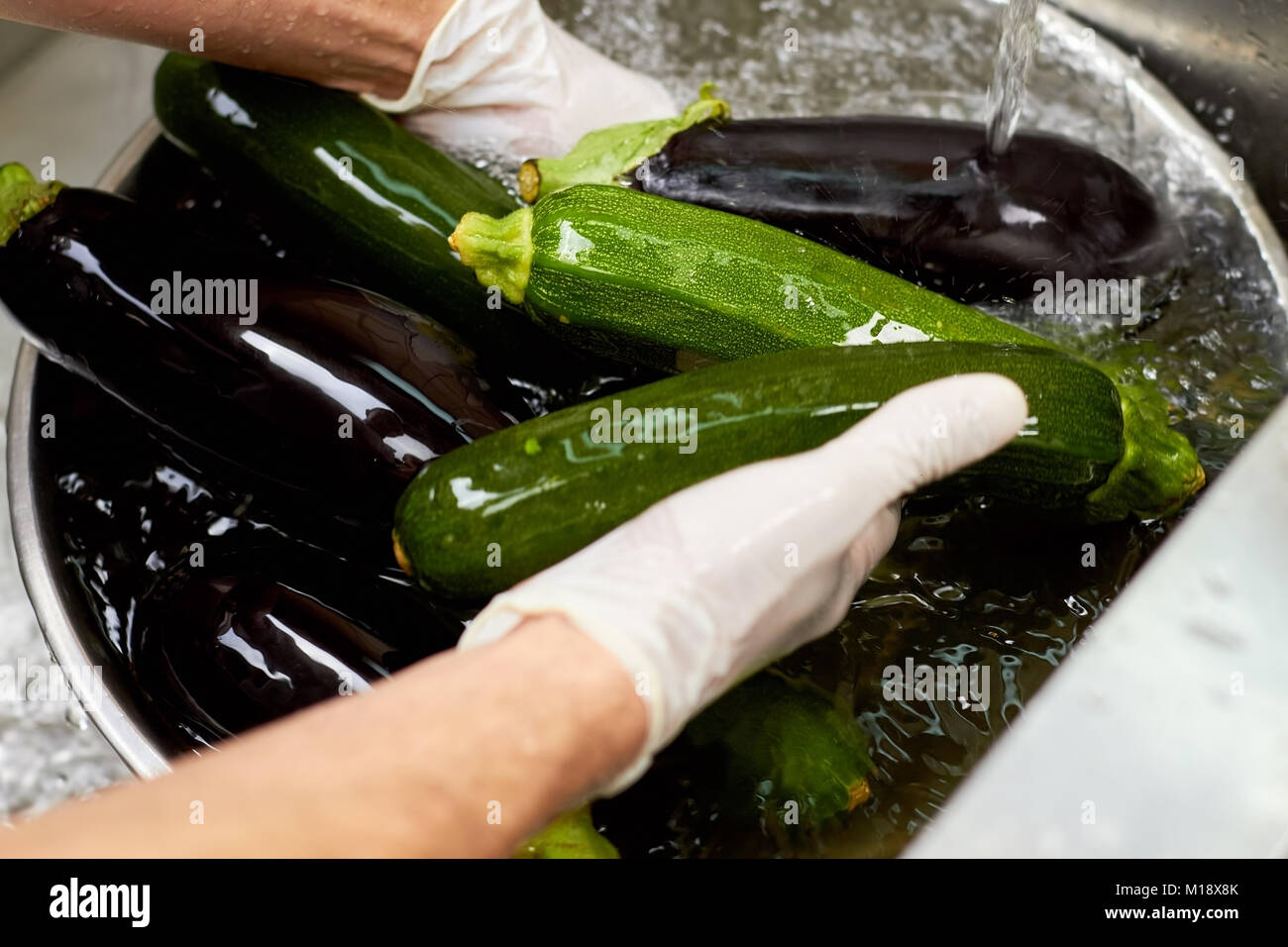 Chef manos lavar verdura bajo el agua del grifo, cerca. Foto de stock